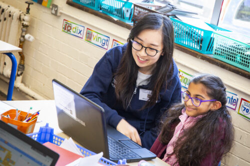 A teacher and learner at a laptop doing coding.