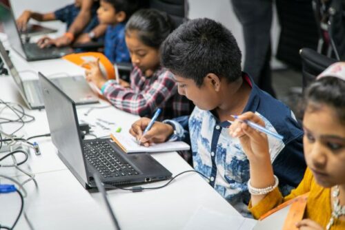 A group of young people plan their projects on laptops.