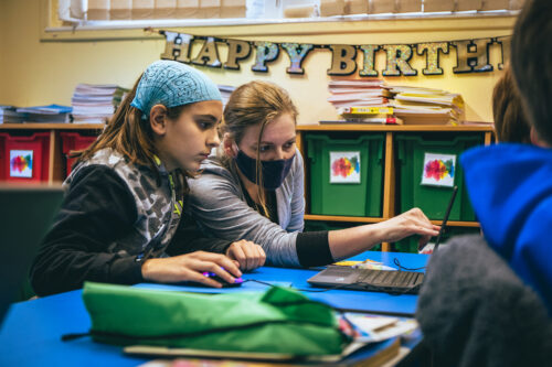 A teacher and a learner at a laptop doing coding.