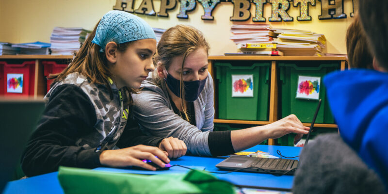 A teacher and learner at a laptop doing coding.