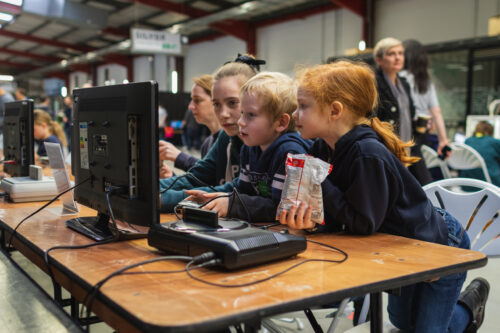 A group of young people work together at a computer.