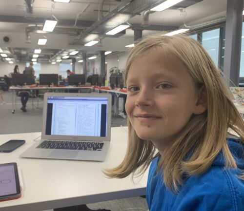 A young person with her coding project at a laptop.