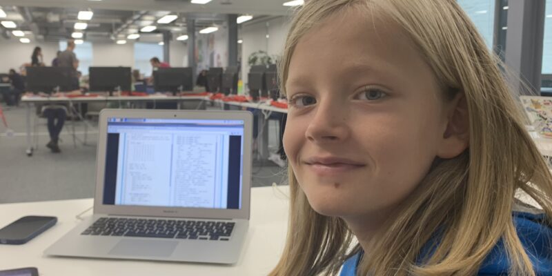 A young person with her coding project at a laptop.