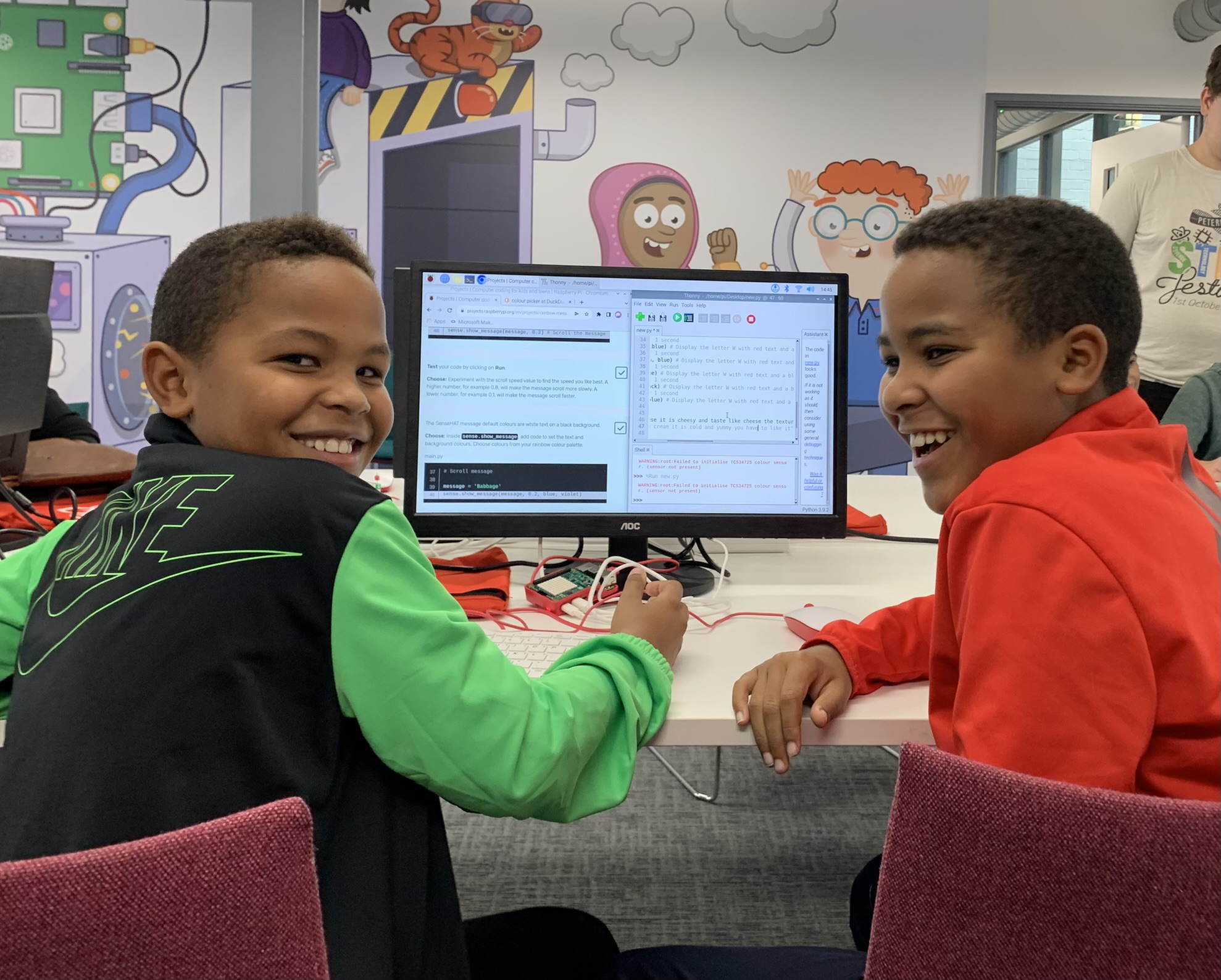 Two children at a coding club with their code on screen.
