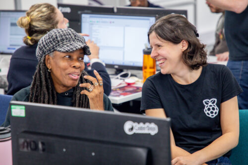 Two smiling adults learn about computing at desktop computers.