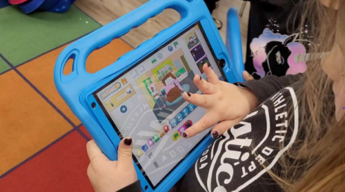 A child select blocks for a ScratchJr project on a tablet.