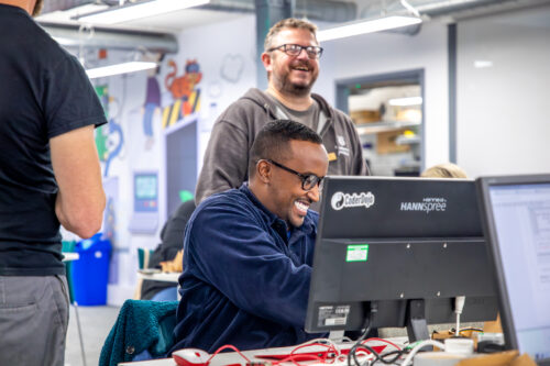 Two adults learn about computing at desktop computers.