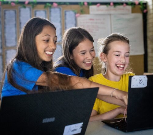 Three learners laughing at a laptop in a Code Club.