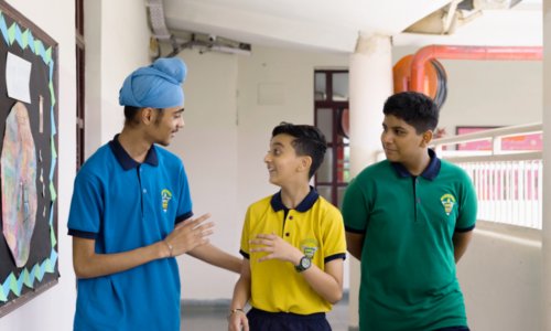 Three students chat outside a school building. 