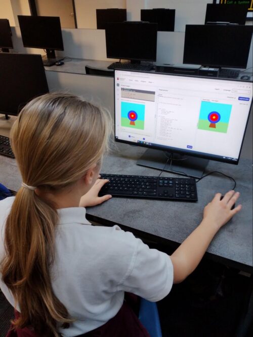 A young person at a computer in a classroom. 