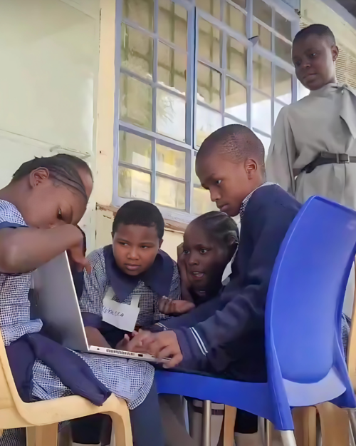 A group of young people coding on a laptop. 