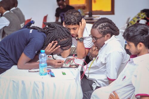 Three learners and an educator do a physical computing activity.