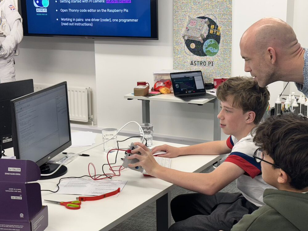 An educator helps young learners with a coding project
