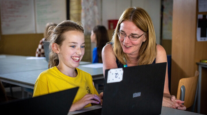 A mentor helps a young person with a coding task at a Code Club.