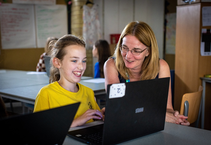 A mentor helps a young person with a coding task at a Code Club.