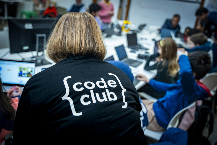 A mentor supports young coders at a Code Club.