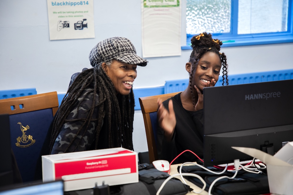 Marie helps a young learner with a coding task in her Code Club.