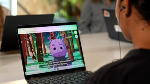 Photo of a young person playing AI Quests on a laptop. The AI Quests character Luna, can clearly be seen on the young person's screen.