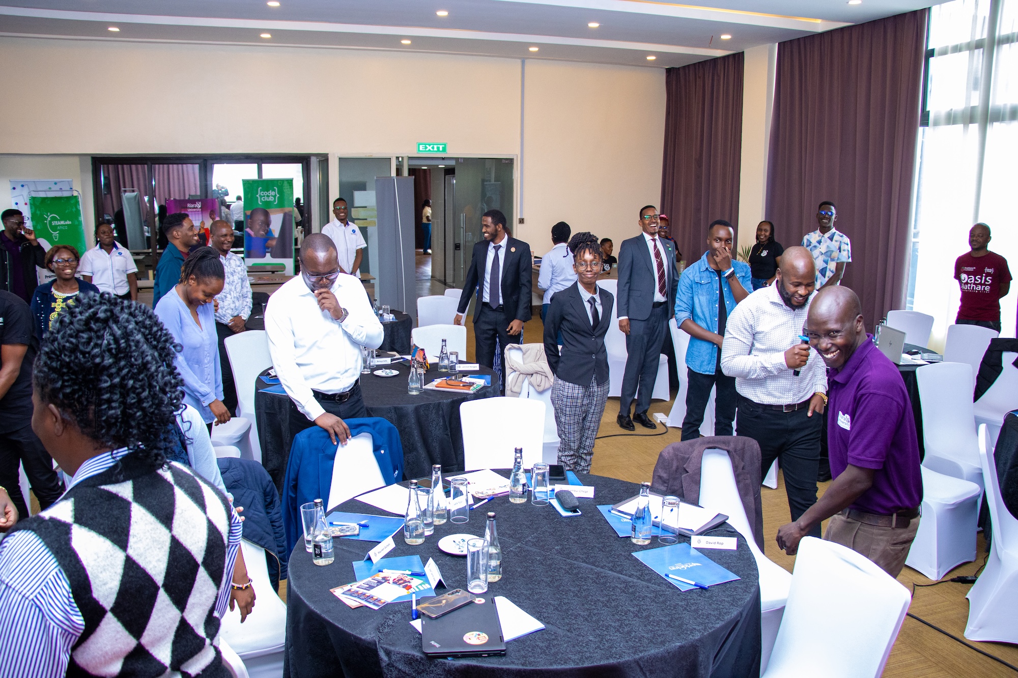 Attendees mingle among tables and chairs at the Raspberry Pi Foundation's Kenya Partner Showcase 2025.