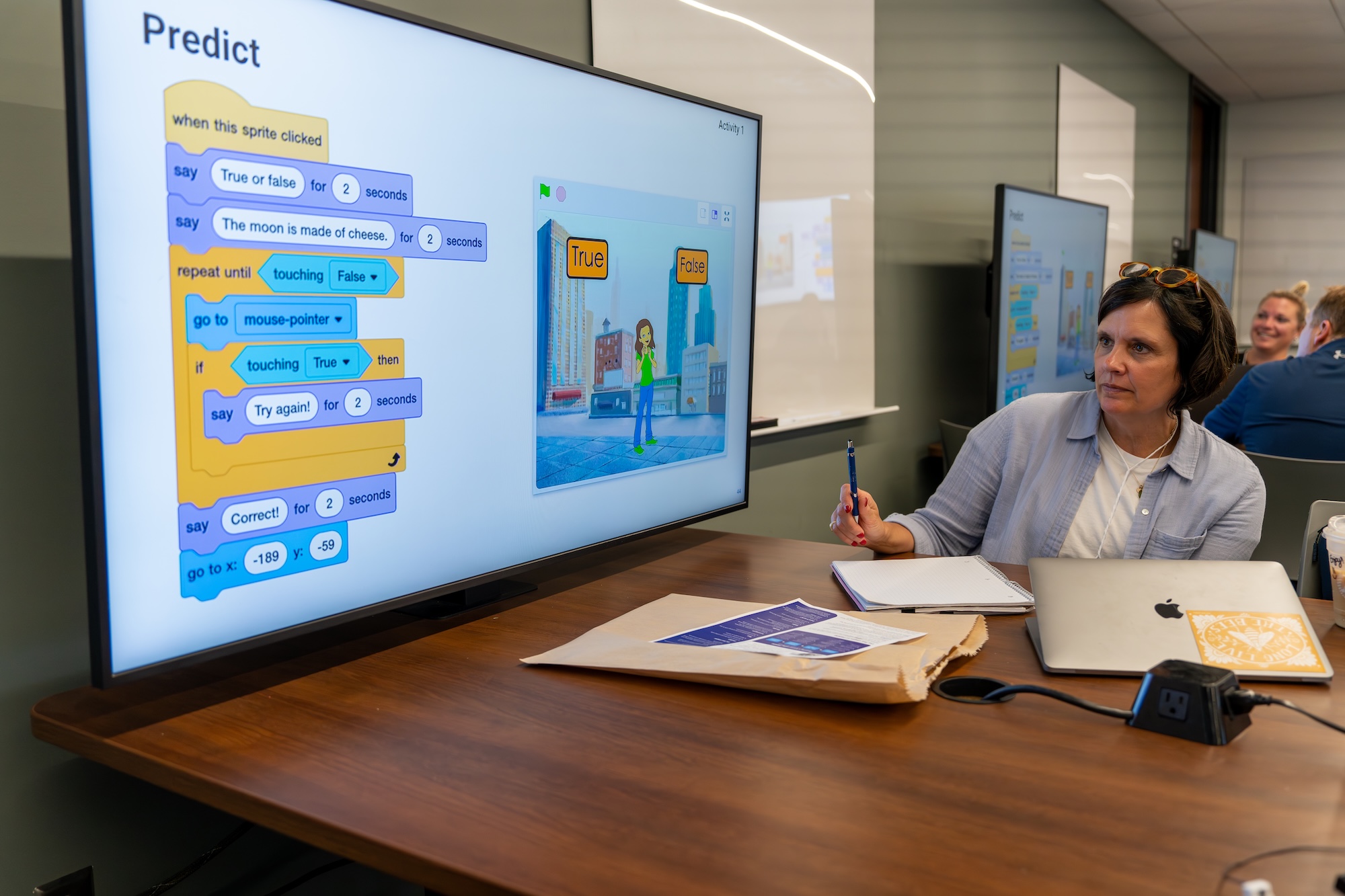 A teacher explores an Experience CS Scratch project on a large screen.