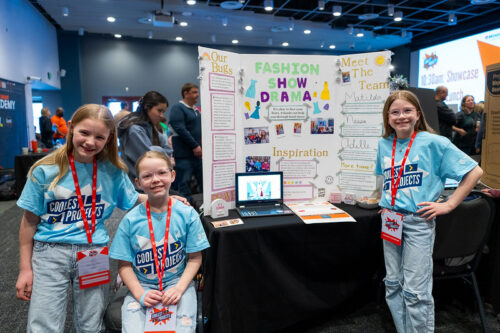 Three children standing in front of their project at Coolest Projects event.