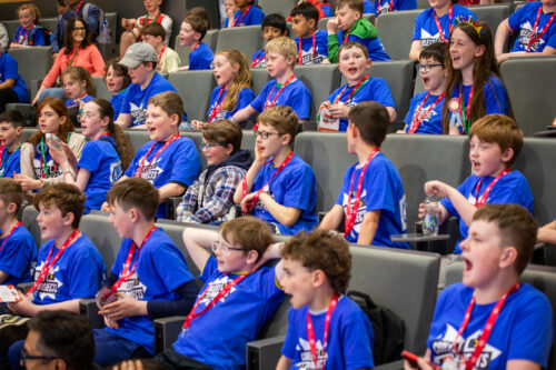 Young people sat in an auditorium wearing Coolest Projects t-shirts.