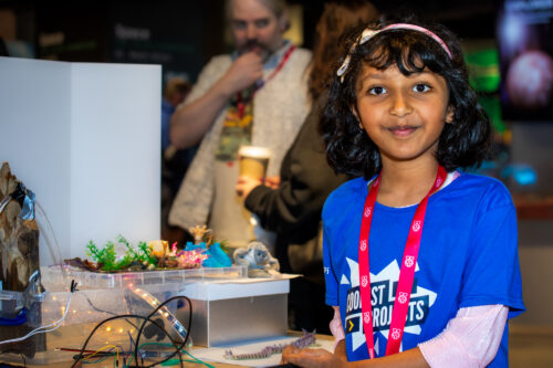 A young person standing next to their project.