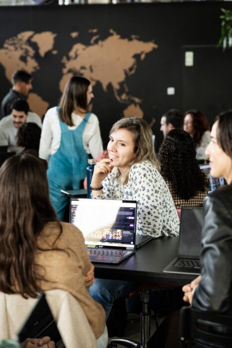 A group of people sat around a table with laptops.
