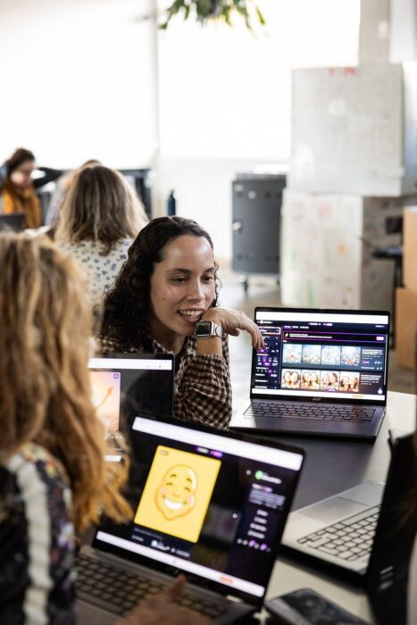 A group of people sat around a table with laptops.