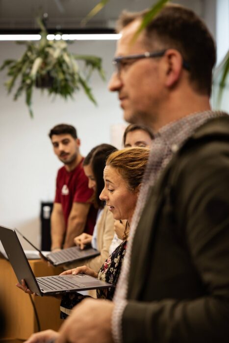 A group of people standing with laptops.