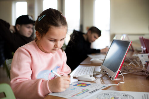 A young person colouring a pixel art design.