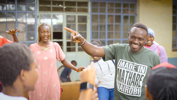 Douglas smiling and talking with young people outside Oasis Mathare.