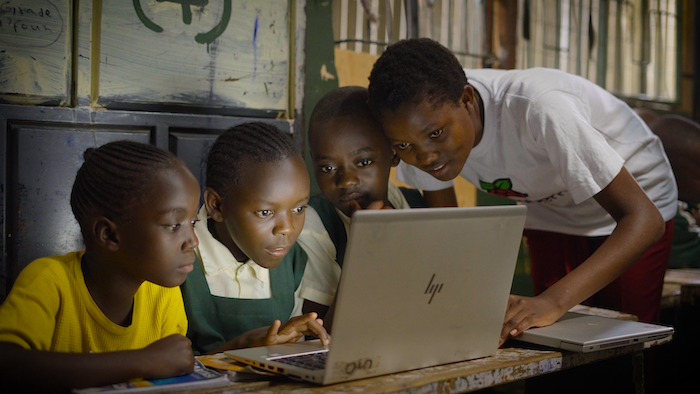 Four young people working together at a laptop.