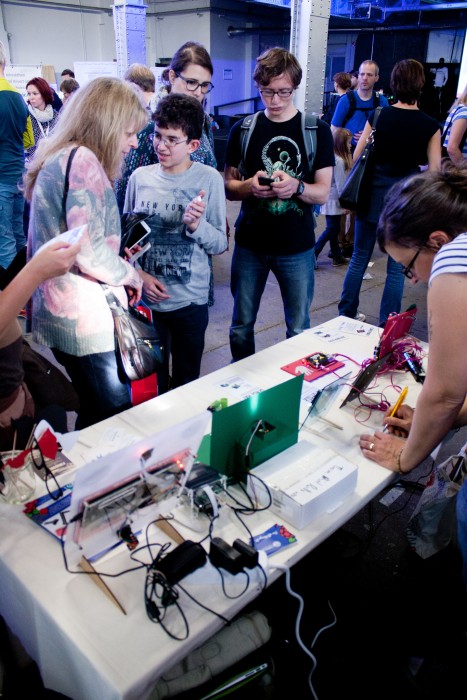 A child explains something to an adult at the Raspberry Pi booth at Maker Faire Berlin 2015
