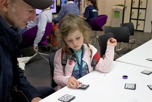 A young girl completes our DOTS board activity, drawing on a printed circuit board with conductive paint