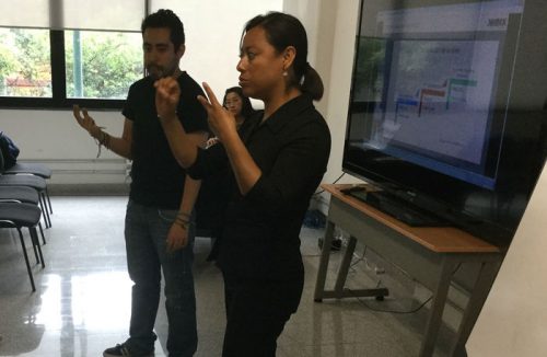 A trainer teaches a class at HolaMundo, and a sign interpreter signs for him